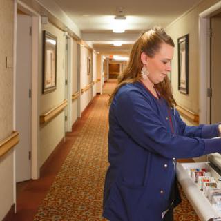 A healthcare worker preparing supplies in a hotel hallway.