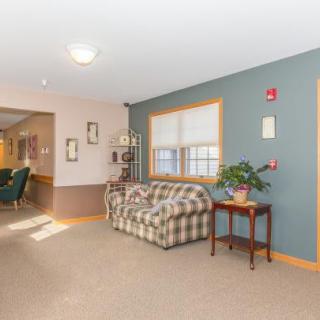 A cozy lobby area featuring a plaid couch and a small table with a plant beside it.
