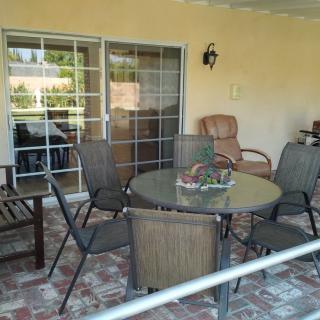 A cozy outdoor patio area with a round table, several chairs, and brick flooring.