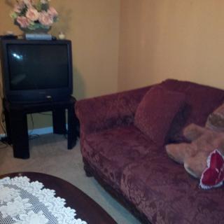 A cozy living room with a plush sofa, decorative pillows, an old-style TV, and a floral arrangement.