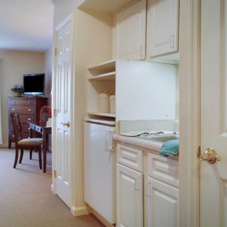 A compact kitchen area opens up to a hallway leading to a living space with a dining table and television.