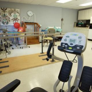 A fitness and rehabilitation room equipped with exercise machines and parallel bars.