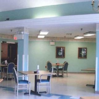 A spacious dining area with tables and chairs, featuring soft lighting and wall decor.