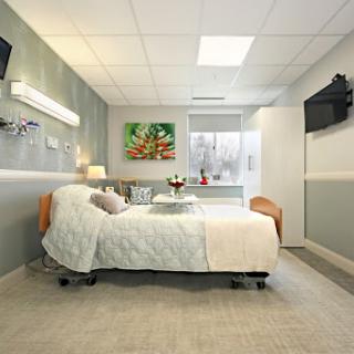 A modern and well-lit hospital patient room featuring a comfortable bed and wall decor.