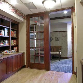 A cozy office lobby with wooden furnishings and a bookshelf, leading to another room.