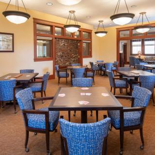 A neatly arranged dining area in a restaurant with blue chairs and wooden tables under elegant lighting.