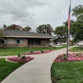 A serene view of a landscaped area with a building and flag, showcasing a well-maintained garden.