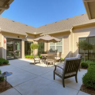 A cozy courtyard with outdoor seating and an umbrella on a sunny day.