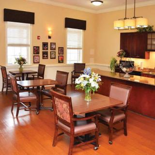 A cozy dining area with neatly arranged tables and chairs, featuring a warm and inviting decor with floral centerpieces.