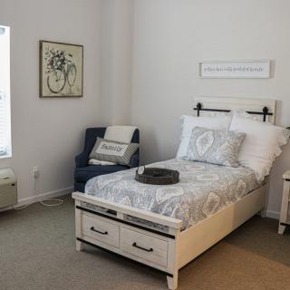 A cozy bedroom with a single bed, matching bedding, an armchair, and wall decor.