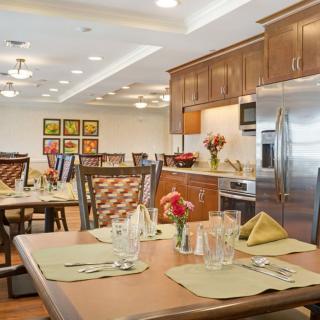 A modern dining area with elegantly set tables and contemporary kitchen appliances.
