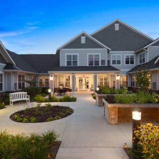 A well-lit residential courtyard with landscaped gardens in the evening.