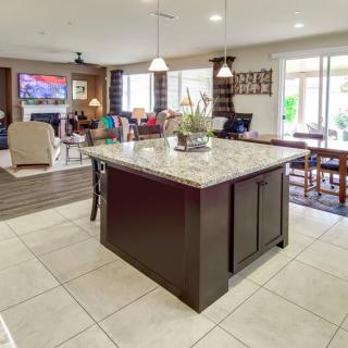 A modern kitchen with a granite island and open floor plan leading to the living and dining areas.