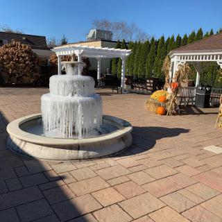 A beautiful outdoor setting featuring a decorative fountain surrounded by autumn decorations and pumpkins.