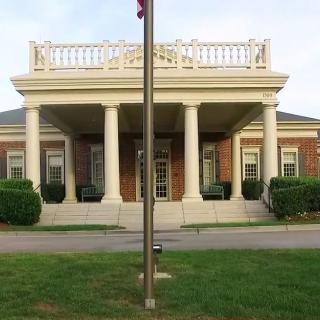 A building with classical architecture featuring columns and a flagpole in front.