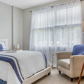 A modern bedroom with elegant decor, featuring a comfortable bed and a cozy armchair by the window.