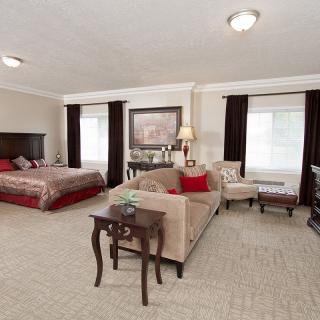 A spacious bedroom with a bed and seating area, featuring elegant furniture and decor.