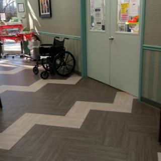 A view of a healthcare facility's waiting area featuring a wheelchair and distinctive floor pattern.