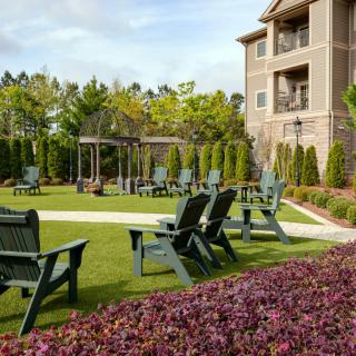 A well-maintained garden with seating areas in front of an apartment building.
