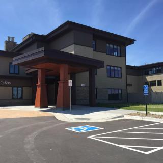 A modern building with a large entrance and adjacent parking lot featuring a handicap space.