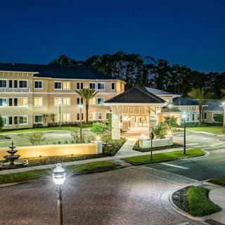 A well-lit hotel entrance at night with surrounding pathways and trees.