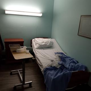 A simple hospital room with a bed and a bedside table.