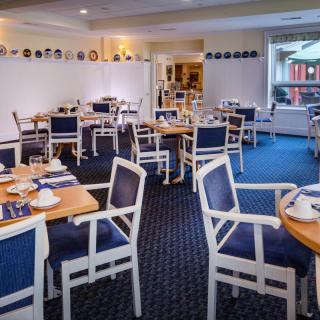 An elegantly set dining room with blue and white decor, featuring neatly arranged tables and chairs.