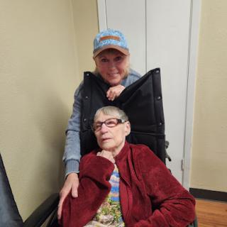 A warm moment shared between a younger woman and an elderly woman sitting in a wheelchair.