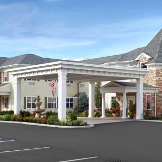 A modern building entrance with prominent columns and a parking area.
