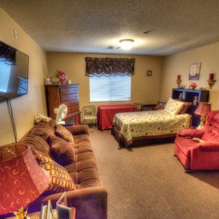A cozy bedroom with a bed, sofa, and television.