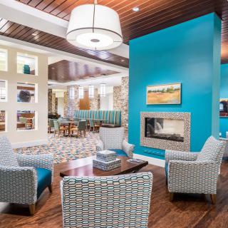A modern living room with a blue accent wall and a cozy fireplace, featuring upholstered chairs and stylish decor.