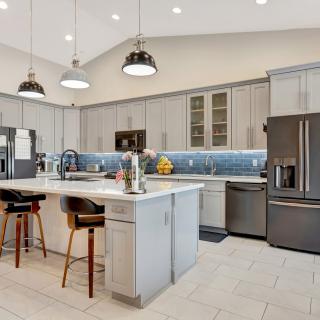 A modern kitchen featuring stainless steel appliances, a central island with bar stools, and elegant pendant lighting.