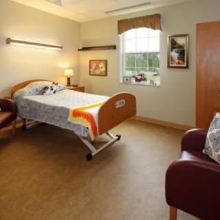 A hospital room with a single bed, chairs, and decor.