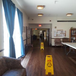 A view of a well-lit lobby area with blue curtains and caution signs on the floor.
