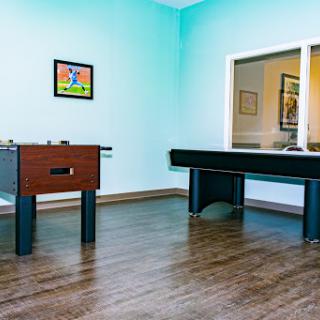 A vibrant game room featuring a foosball table and an air hockey table with blue walls.