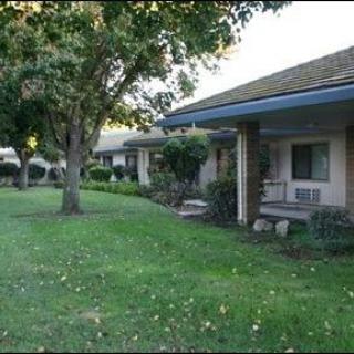 A suburban residential area with houses featuring front porches and a well-maintained lawn.
