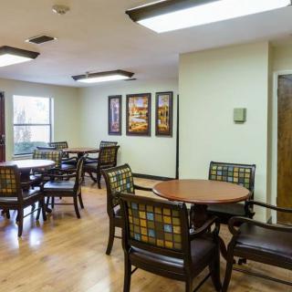 A cozy dining area with several tables and chairs, featuring wooden flooring and wall art.