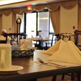 An empty restaurant dining area with neatly set tables and folded napkins.