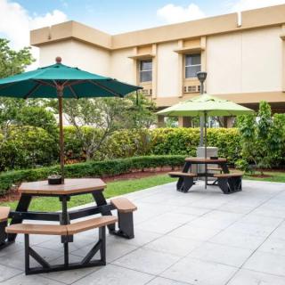 A peaceful outdoor patio area with tables and umbrellas surrounded by greenery.