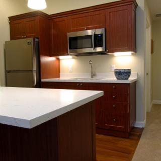 A modern kitchen with wooden cabinets, a stainless steel microwave, and a large countertop.