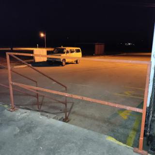 A quiet night scene in a parking lot, featuring a van parked under the glow of streetlights.