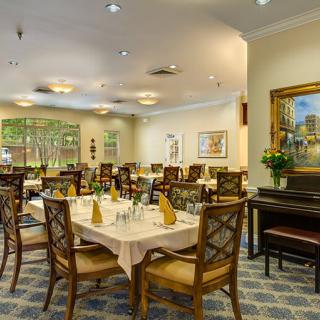 An elegantly furnished dining room with neatly arranged tables and chairs, showcasing tasteful decor and a warm ambiance.