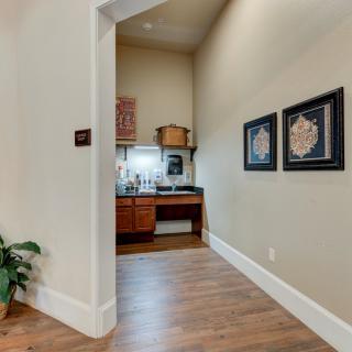 A hallway with wooden flooring, featuring a countertop area and framed artwork on the wall.