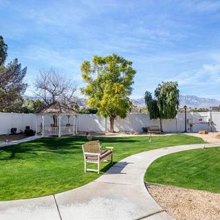 A well-maintained backyard featuring a grassy area, trees, and a curved pathway leading to a bench.