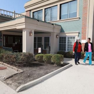 Two individuals walking outside a building on a sunny day.