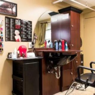 A cozy barbershop interior with a styling station, mirror, and hair care products.
