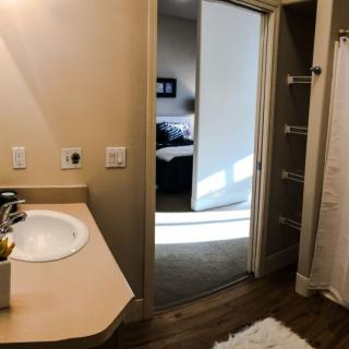 A bathroom with a view into a bedroom, featuring a sink and mirror.