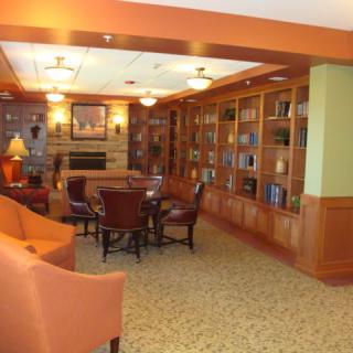 A cozy library with wooden bookshelves, comfortable seating, and a reading table.