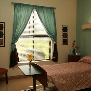 A cozy hospital room with a single bed and a window with blue curtains.
