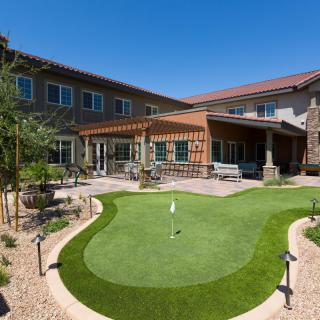 A modern building with a beautifully landscaped courtyard featuring a golf putting green.